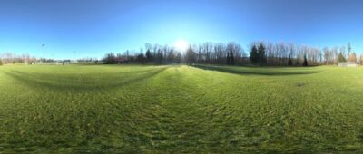 An outdoor HDRI image of a green field and sunny sky from Poly Haven.