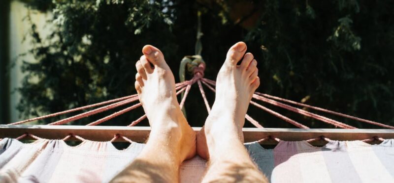 A man with his feet resting on a hammock. 