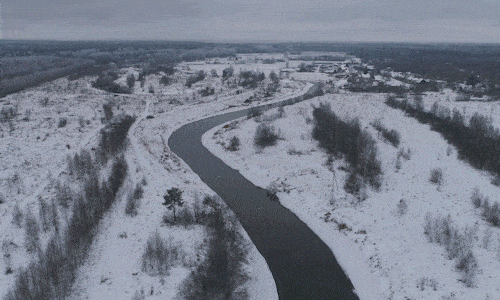 Aerial footage of a river flowing through snow-covered land.
