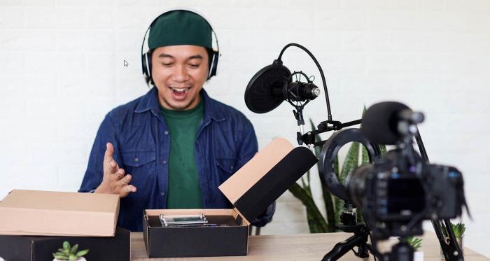 A Youtuber doing a product unboxing in front of a camera and microphone. 