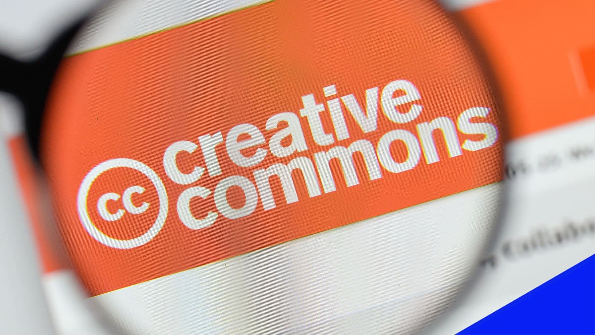The orange creative commons logo is viewed through a magnifying glass.